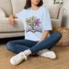 Book and Flowers T-Shirt - Yellow and Purple Lilies Design, Literary Botanical Art Tee, Unisex Gift for Readers and Nature Lovers